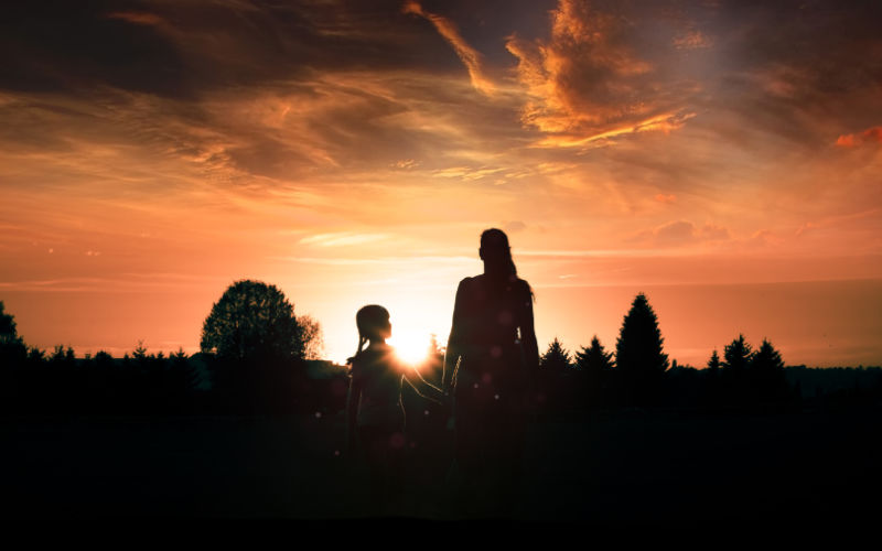 mother and child facing sunset
