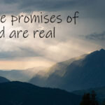 Majestic mountains with sunrays pushing through the clouds. Text says, The promises of God are real